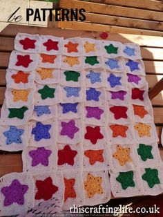 a crocheted blanket with stars on it sitting on a wooden bench next to a chair