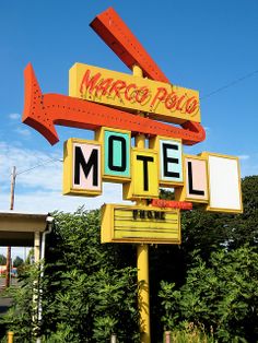 a yellow motel sign with an arrow pointing to the right and another red one on top