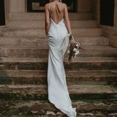 a woman in a white dress is standing on some steps with her back to the camera