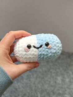 a person holding a small stuffed animal in their left hand with eyes drawn on it