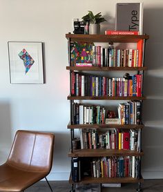 a bookshelf filled with lots of books next to a brown chair and wall