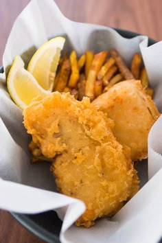 fried fish and fries in a basket with lemon wedges