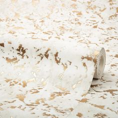 a roll of white and gold foiled paper on top of a tablecloth covered floor