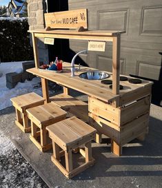 a wooden table with benches and a sink in front of a garage door that has snow on the ground