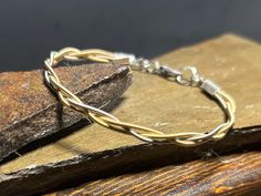 a gold bracelet sitting on top of a piece of wood