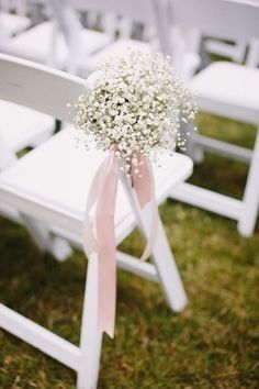 a bouquet of baby's breath sits on the back of a white folding chair