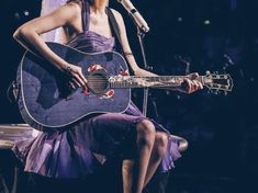 a woman in a purple dress holding a guitar