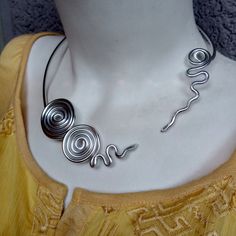 Sharm Open Metal Choker. Silver Necklace. Modern Style. Spiral Aluminum Silver Necklace. Statement Necklace.Bridal Jewelry. Bold Designe. Handmade. This spiral shape necklace is a statement piece, the perfect accessory to complete a stunning outfit look. Ideal for a casual fashion style. Materials:  - Aluminum wire (3 mm). The material I use to wrap aluminum wire, that means, is not heavy at all. Aluminum is lightweight and will never tarnish. I give it a slightly hammered texture and wrap the glass stone with it. SIZE: The necklace is 54 cm/ 21 inches in circumference  COLOR:  Silver, aluminum  wire Try to keep it away from water. Shipping time: This item is finished product and it will be sent immediately. Shipping time is 1 to 4 weeks (depends of your Custom office and Post office).  Th Silver Spiral Jewelry For Weddings, Silver Spiral-shaped Wedding Jewelry, Spiral Silver Wedding Jewelry, Silver Spiral Wedding Jewelry, Silver Spiral Metal Necklaces, Silver Spiral Metal Necklace, Adjustable Spiral Silver Necklace, Unique Silver Choker For Wedding, Silver Spiral Jewelry For Party