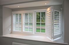 an empty room with white shutters on the windows