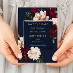 two hands holding up a wedding card with flowers on the front and back, in navy blue