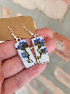 a pair of earrings with blue flowers painted on them