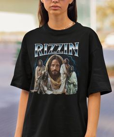 This awesome Rizzin Jesus shirt is soon to become your new favorite! Please note: This is a Gildan t-shirt. If you would like a different brand of t-shirt, please send us a message.  Want a different design or color? Just let us know and we'll make it happen!  FIT & SIZING: * These Gildan unisex heavy cotton tees fit like a well-loved favorite. * Classic fit tees are comfortable and flattering for both men and women. * Please see the size chart in the photos to obtain an accurate size. Measure o Controversial Shirts, Y2k Cotton Shirt With Funny Print, Ironic Shirts, 90s Cotton Shirt With Funny Print, Vintage Black T-shirt With Funny Text, 90s Style Cotton T-shirt With Funny Print, Meme Shirts Graphic Tees, Jesus Funny, Iron Shirt