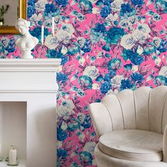 a white chair sitting in front of a pink wall with blue and white flowers on it