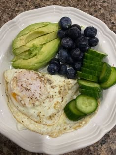 a plate with eggs, cucumbers and blueberries on it