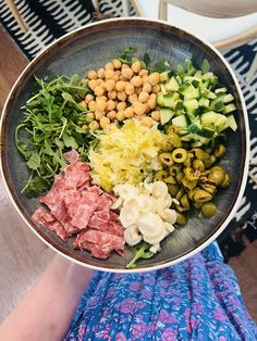 a person holding a metal bowl filled with different types of food