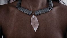 a woman wearing a necklace with a feather on it