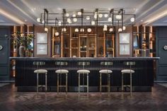 a bar with four stools in front of it and lots of lights hanging from the ceiling