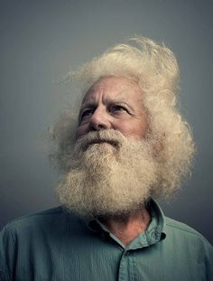 an old man with a long white beard wearing a green shirt and looking up at the sky