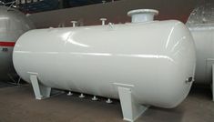 a large white tank sitting inside of a building next to another metal container on the ground