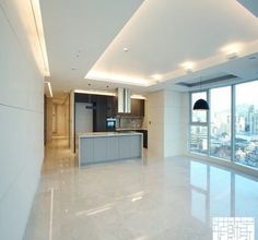 an empty kitchen and living room in a large modern apartment with floor to ceiling windows