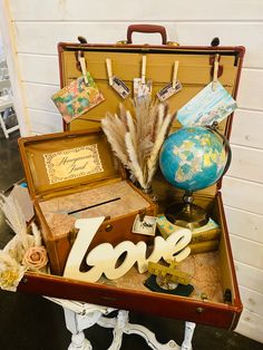 an open suitcase filled with lots of items on top of a wooden table next to a wall