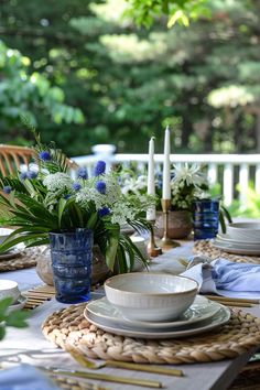 the table is set with plates, bowls and vases on it's placemat