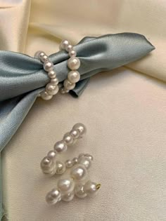 two pearls are attached to the lapel of a white shirt with blue satin bow