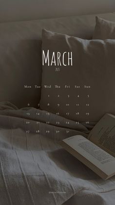 an open book sitting on top of a bed next to a pillow with the word march