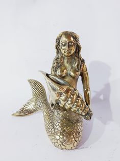 a gold colored mermaid figurine holding a fish