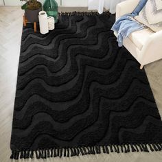 a black area rug with fringes on the floor in front of a white chair