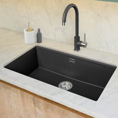 a black kitchen sink sitting under a faucet next to a counter top with soap dispenser