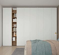 a bedroom with white closets and bookshelves next to a bed in front of a bookcase