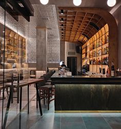 an empty bar with lots of bottles on the shelves and tables in front of it