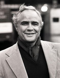 a black and white photo of a man in a suit jacket smiling at the camera