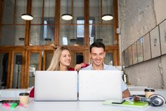 two people sitting at a table with laptops in front of them - stock photo - images