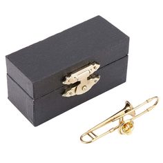 a black box with a gold tie clip in it and a pair of scissors next to it