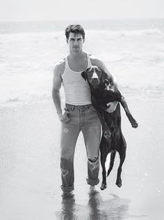 a man holding a dog on the beach