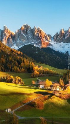 the mountains are covered in snow and green grass, with houses on either side of them