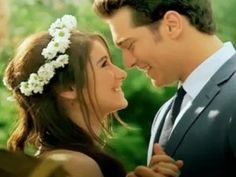 a man and woman standing next to each other with flowers in their hair looking at each other