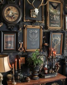 there are many framed pictures on the wall with candles in front of them and two deer heads mounted to the wall