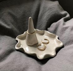 two gold wedding rings are on a white tray next to a pair of hoop earrings