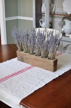 some lavender plants are in a wooden box on a tablecloth with red and white striped napkins