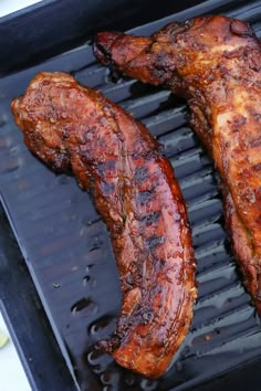 two pieces of meat are cooking on a grill