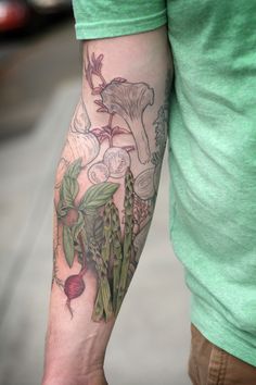 a man with a tattoo on his arm holding a radish and mushroom plant