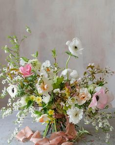 a vase filled with lots of white and pink flowers on top of a gray table