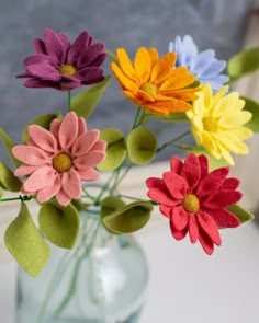 colorful felt flowers in a glass vase on a window sill