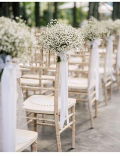 the aisle is lined with chairs and decorated with baby's breath flowers, tied in white ribbon