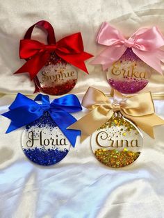 three personalized christmas ornament ornaments with ribbons and bows on white fabric background