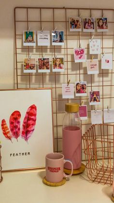 there is a coffee cup and pink mug on the counter next to a wall with pictures