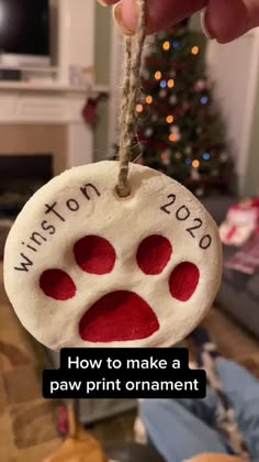 someone is holding up a paw print ornament